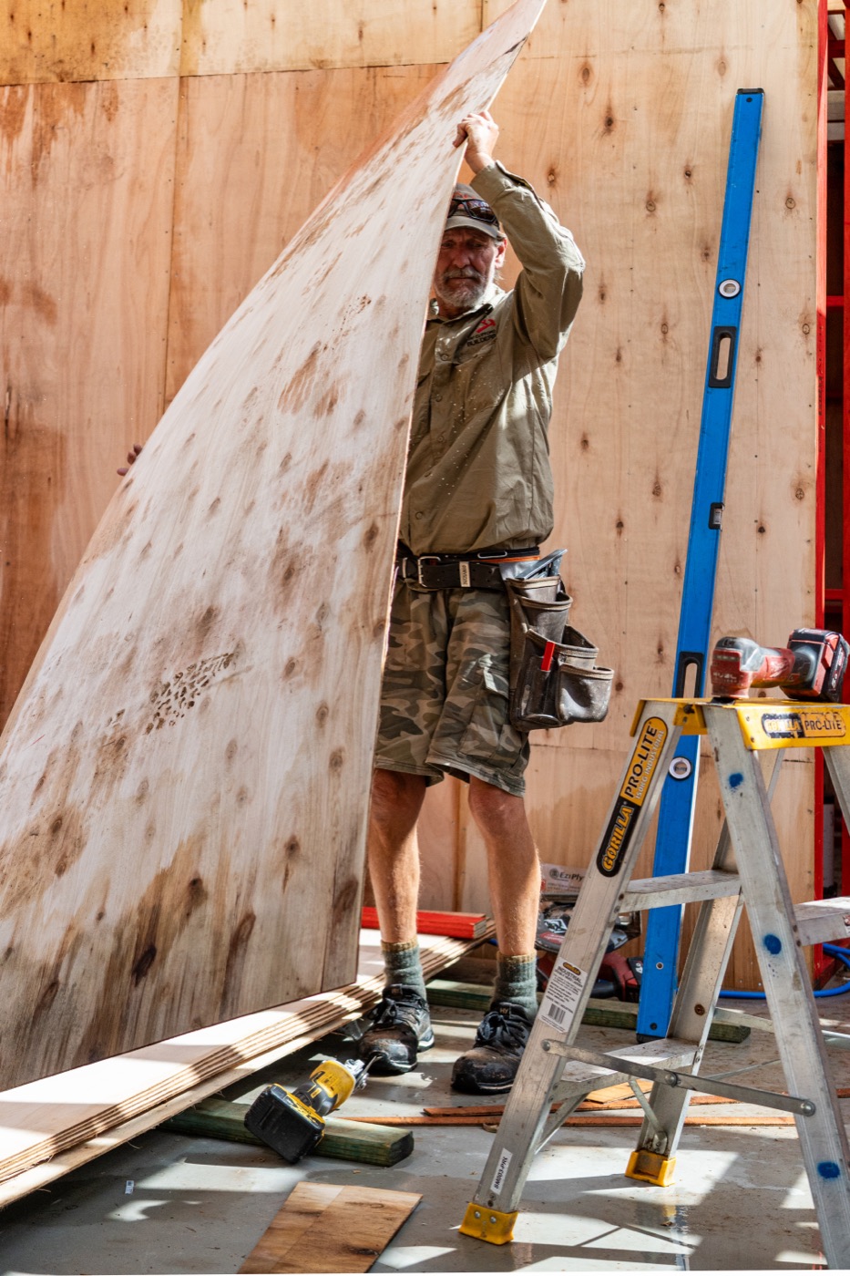 Lifting a plywood sheet into place against the new frame