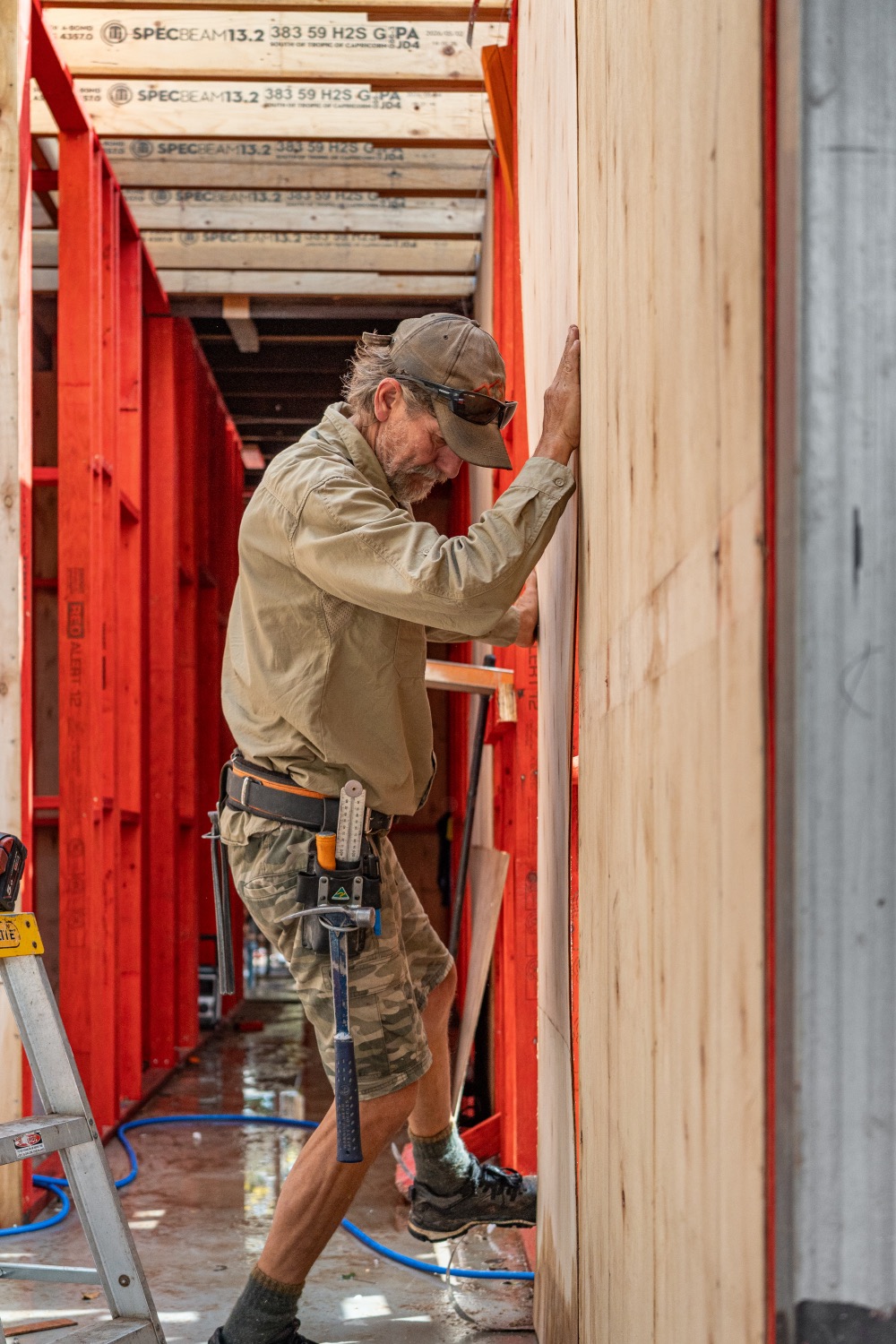 A carpenter fitting a sheet into new red timber framing