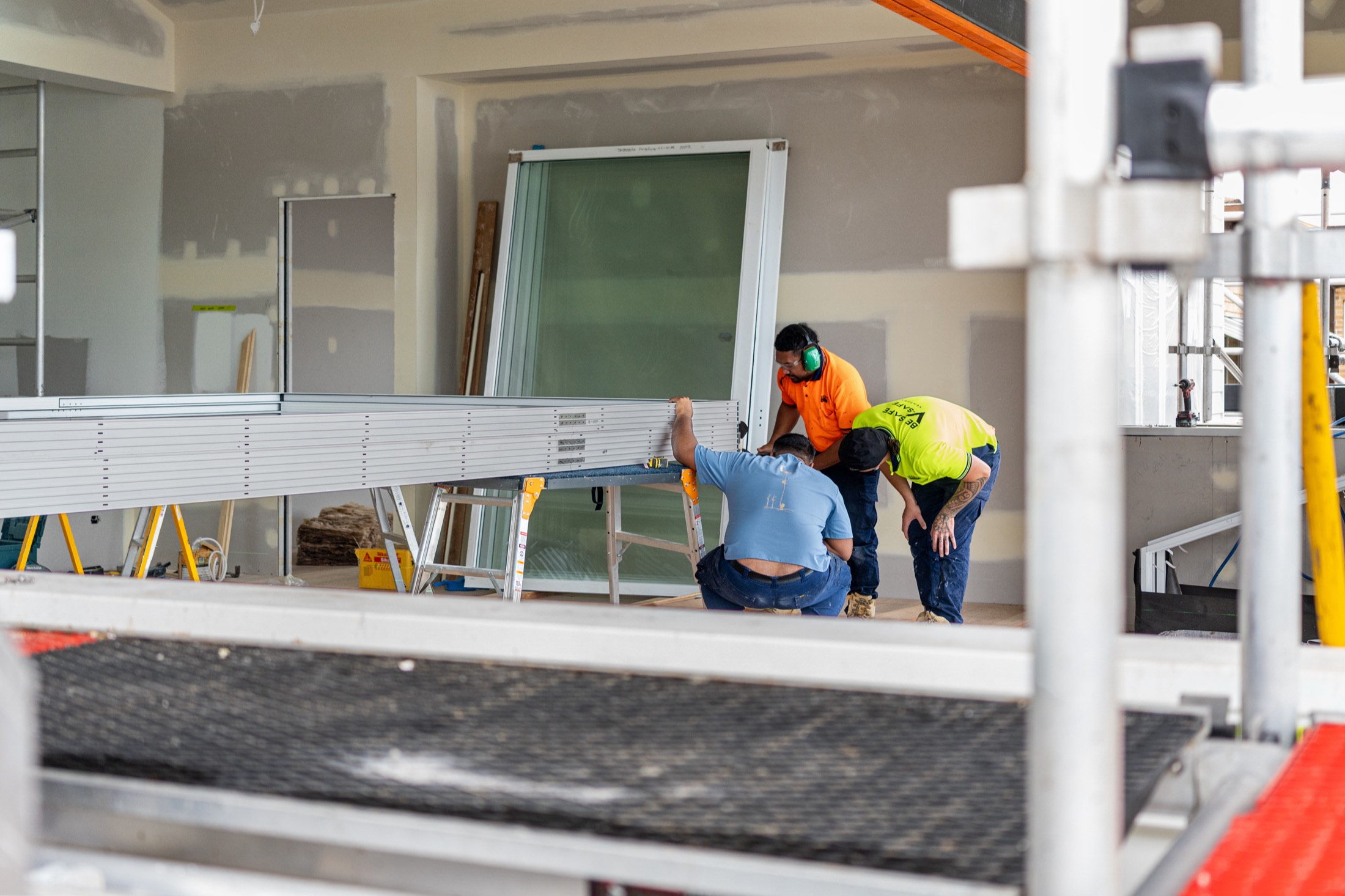 The crew lifting a window frame onto the scaffold deck