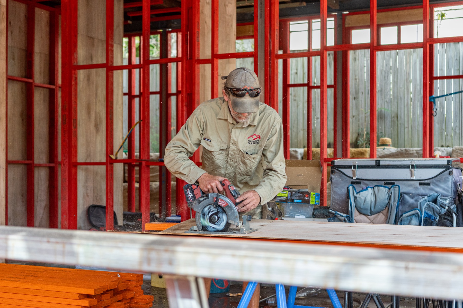 A carpenter cutting timber at a bench inside the new frame